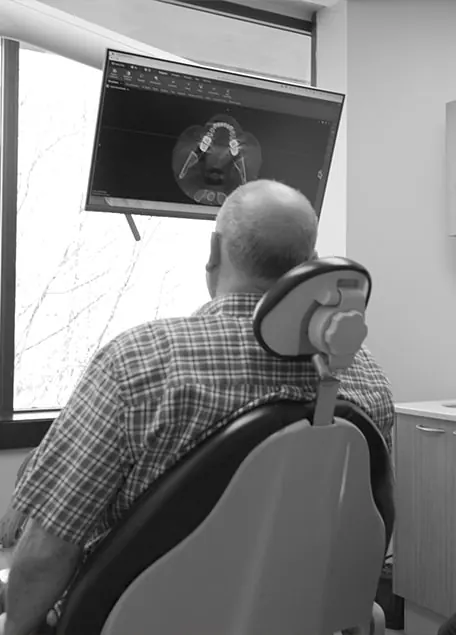 Patient in the dental chair looking at a 3D scan of his teeth on a monitor