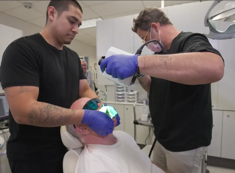 Dental technician comparing porcelain shade tabs to a patient's smile