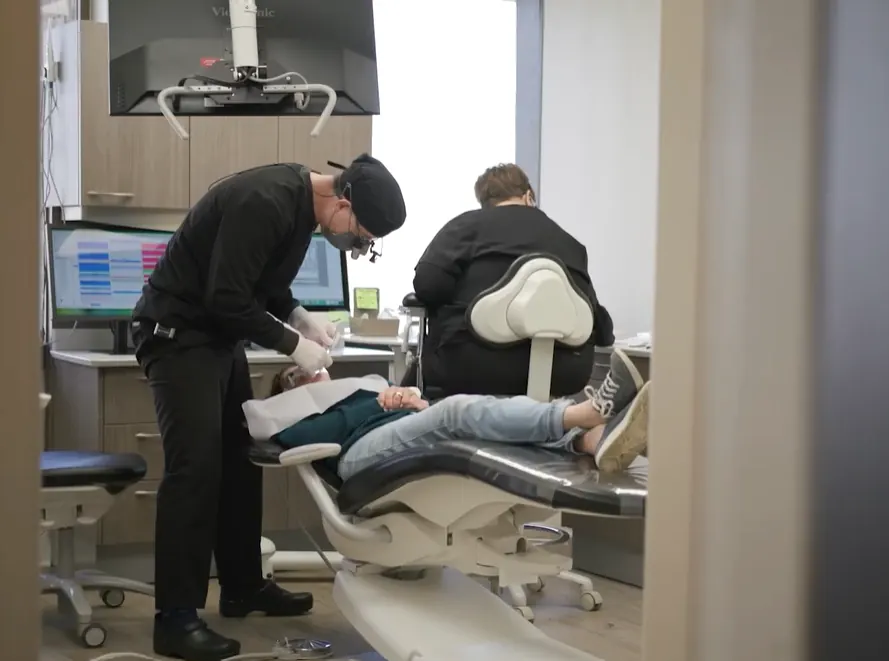 Dentist leaning over a patient reclined in the dental chair