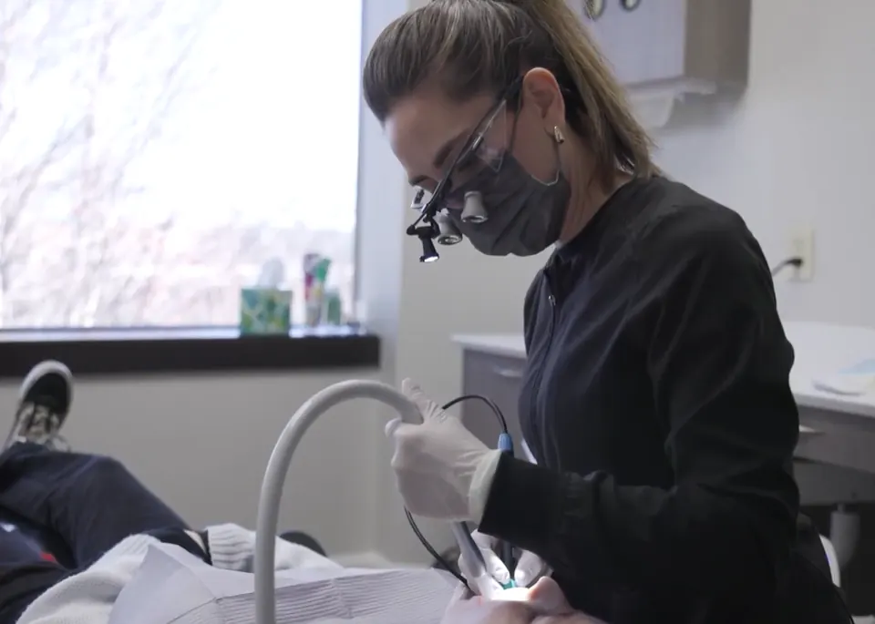 Dental team member wearing loupes treating a patient in the chair
